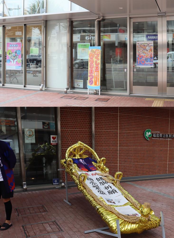 福島わらじ祭りの装飾が施された金色のわらじと、背景にある賑やかなポスターが見える風景。