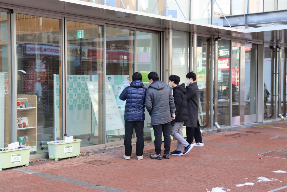 合格発表を確認する学生たちが、福島駅前キャンパスのエントランスホール前に集まっている様子。