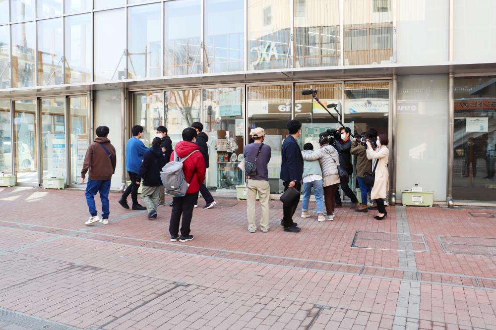 合格発表を待つ受験者たちが福島駅前キャンパスの前に集まり、掲示板を確認している様子。