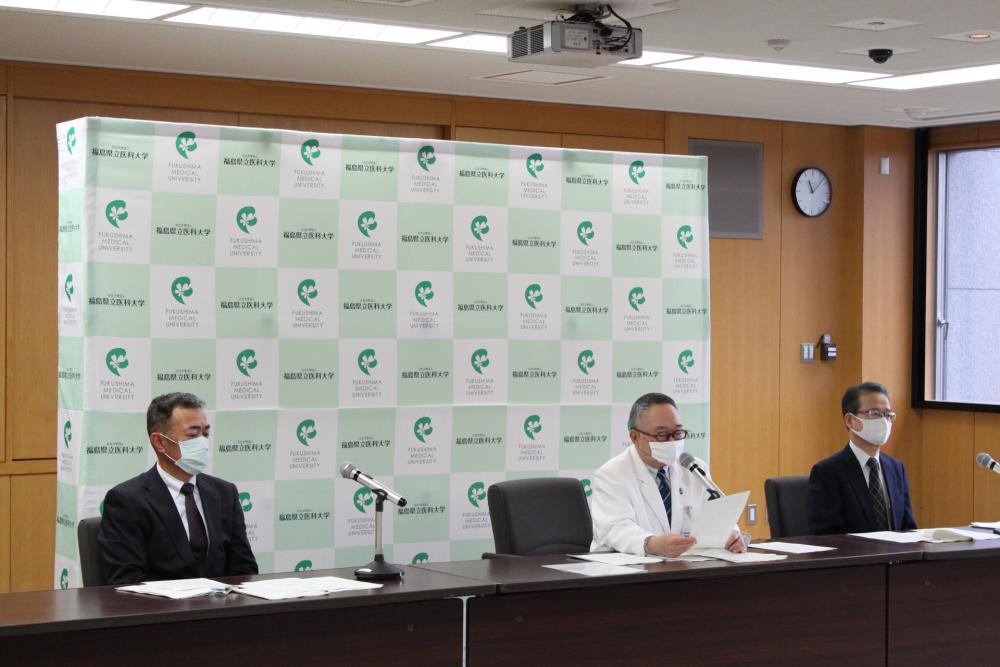 保健科学部の設置認可に関する記者会見の様子。マスクを着用した3人の男性がテーブルに座り、発表を行っています。
