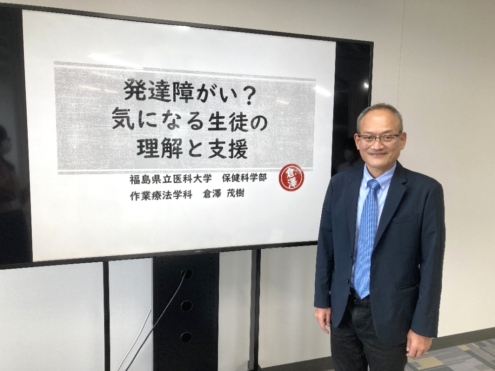 発達障害に関する講演を行う福島県立医科大学の倉澤教授とそのプレゼンテーションボード。