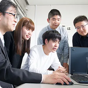 学生たちがパソコンの画面を見ながら議論している様子。教育現場での協力的な学びを表現。
