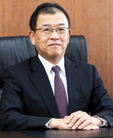 医学部長の藤森敬也氏が椅子に座り、真剣な表情でカメラを見つめているポートレート。