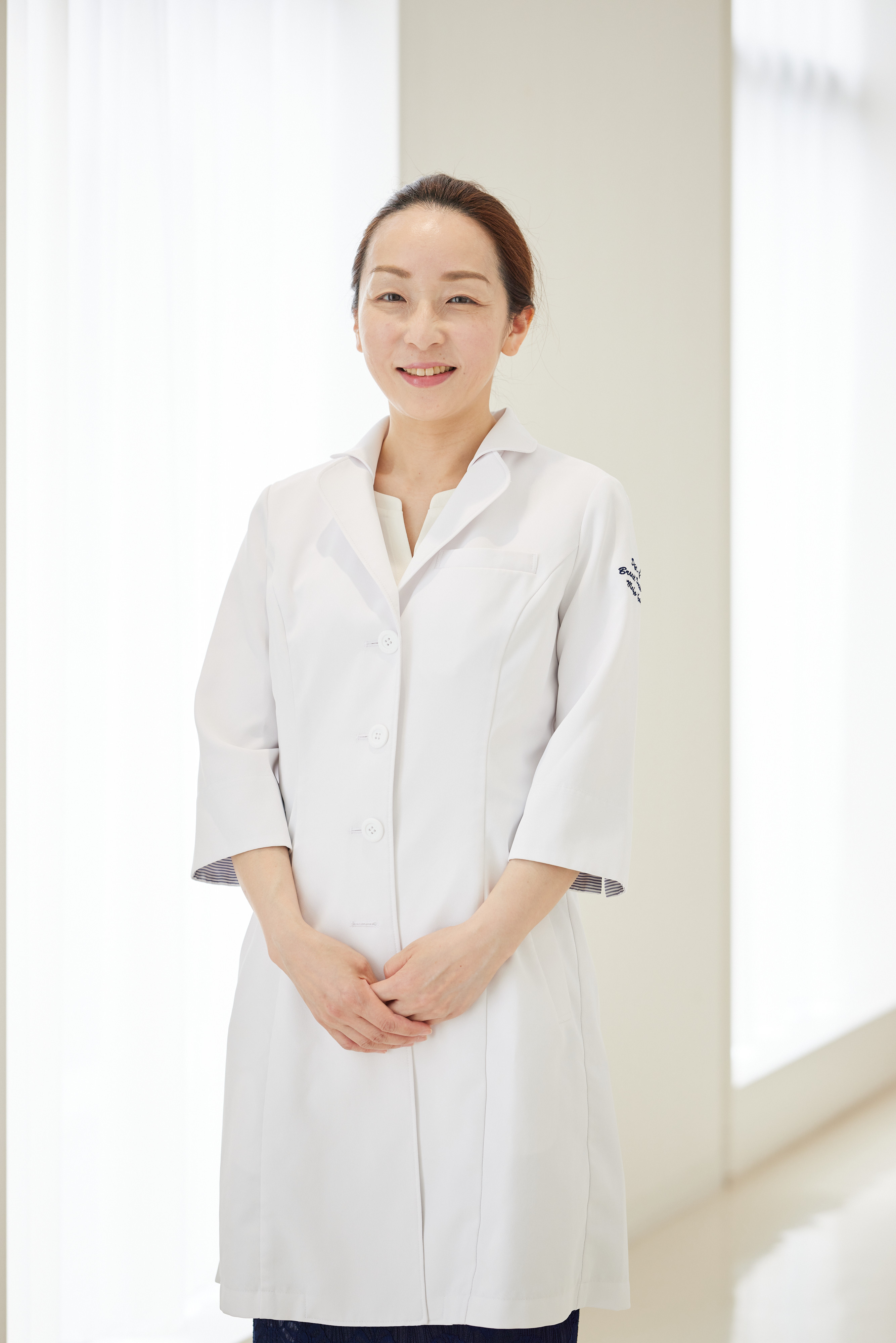 福島県立医科大学の講師、岡野舞子さんが白衣を着て廊下で立っている写真。