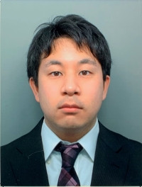佐藤洋太さんがスーツを着て微笑んでいるポートレート。