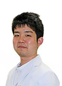 大学院生の小河原崚が白衣を着て微笑んでいるポートレート。研究に励む姿勢が伝わる一枚。