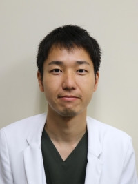 大学院生の大河内諭が白衣を着て微笑んでいるポートレート。研究に励む姿勢が伝わる一枚。