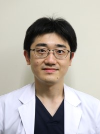 大学院生の関根虎之介さんが白衣を着て微笑んでいるポートレート。福島県立医科大学で基礎研究に取り組む姿。