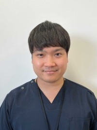 大学院生の上田捷太さんが医療用の服を着て微笑んでいるポートレート。