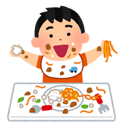 食べ物で汚れた服を着た男の子が、楽しそうに食事をしている様子。テーブルには皿やフォークが散らばっている。
