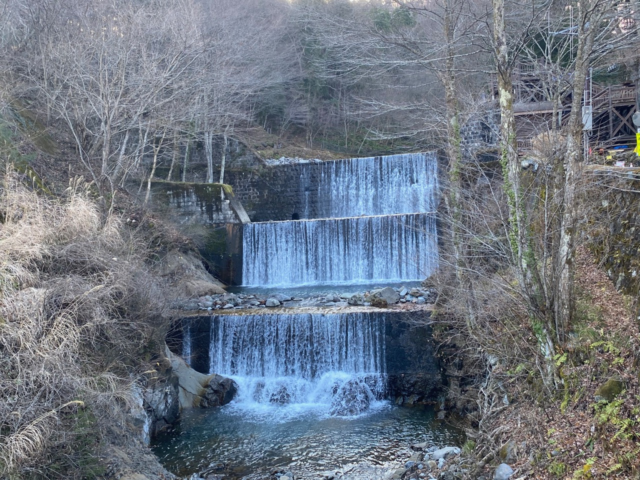 ３段続く小滝の周囲は木々が薄く覆われ、岩が点在する静かな風景。
