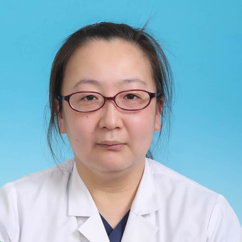 医療用白衣を着た松本佳子講師のポートレート。背景は青色。
