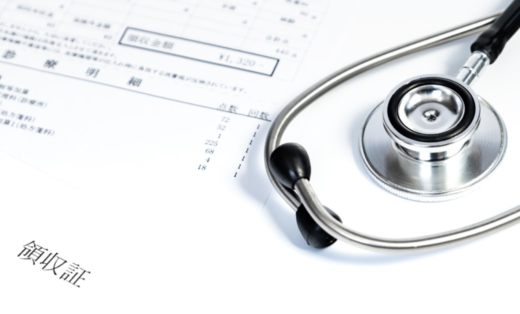 聴診器が医療費の明細書の上に置かれている画像。