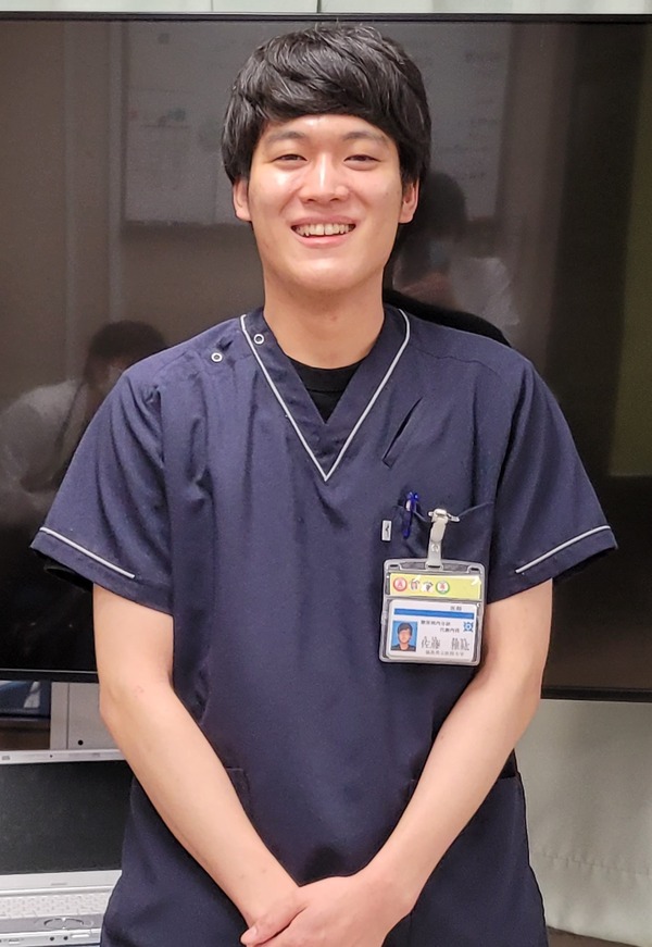 福島県立医科大学のスタッフ、佐藤雅紘さんが笑顔で立っている写真。