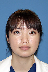 医療従事者の芦澤舞さんの顔写真。白衣を着用し、青い背景の前で微笑んでいる。