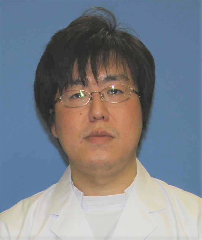 医療白衣を着た望月翔太朗さんのポートレート。背景は青色。