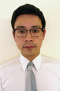 福島県立医科大学の菅家康之氏のポートレート。白シャツにネクタイを着用し、眼鏡をかけた真剣な表情。