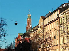 スウェーデンの街並み、青空の下に高い時計塔と色とりどりの建物が並ぶ風景。