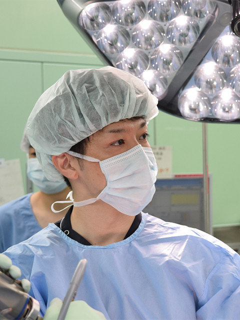 手術室でマスクとキャップを着用した医師が、手術に集中している様子。