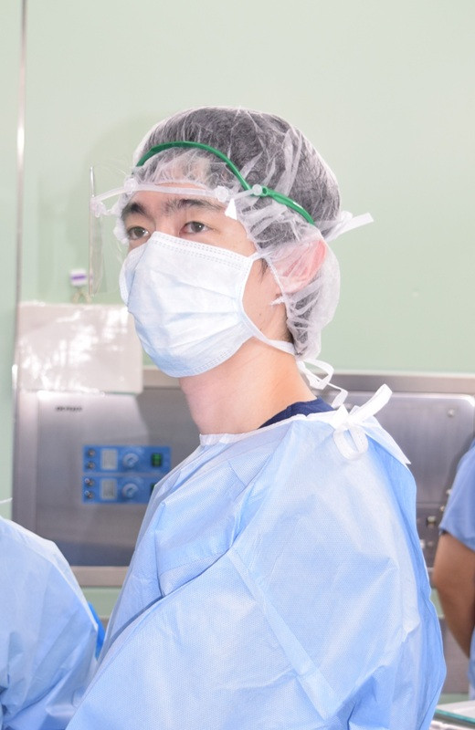 手術室でマスクとキャップを着用した医師が、手術に集中している様子。