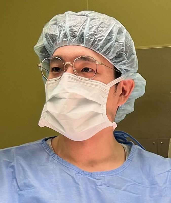 手術室でマスクとキャップを着用した医師が、手術に集中している様子。