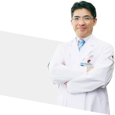 医療用白衣を着た男性医師が腕を組んで微笑んでいる姿。背景はシンプルで、医療の専門性を強調。
