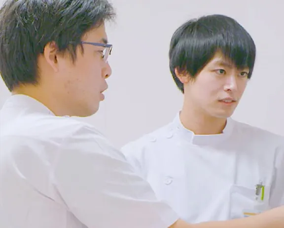 若手外科医が教育プログラムについて話し合う様子。医療器具が置かれた環境でのチームワークを重視した研修風景。