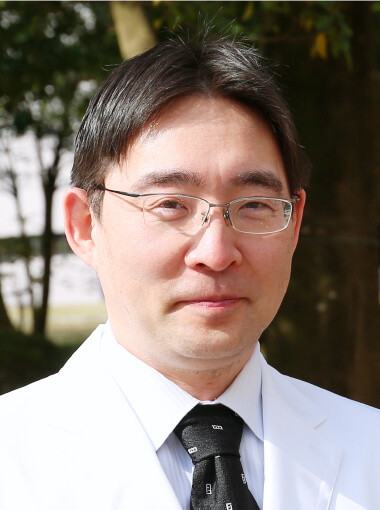 肝胆膵・移植外科学講座の博士研究員、芳賀淳一郎氏のポートレート。白衣を着て微笑む姿。