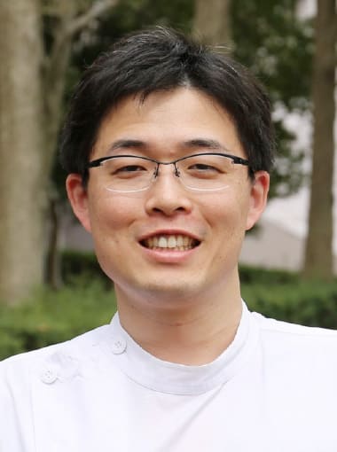 肝胆膵・移植外科学講座の助手、武藤亮さんの笑顔のポートレート。福島県出身で、癌診療に取り組む医療人。