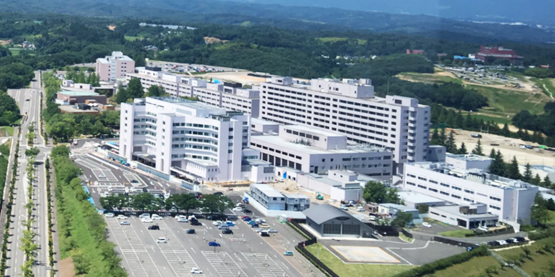 福島県立医科大学のキャンパス全景、周囲には緑豊かな山々が広がる。