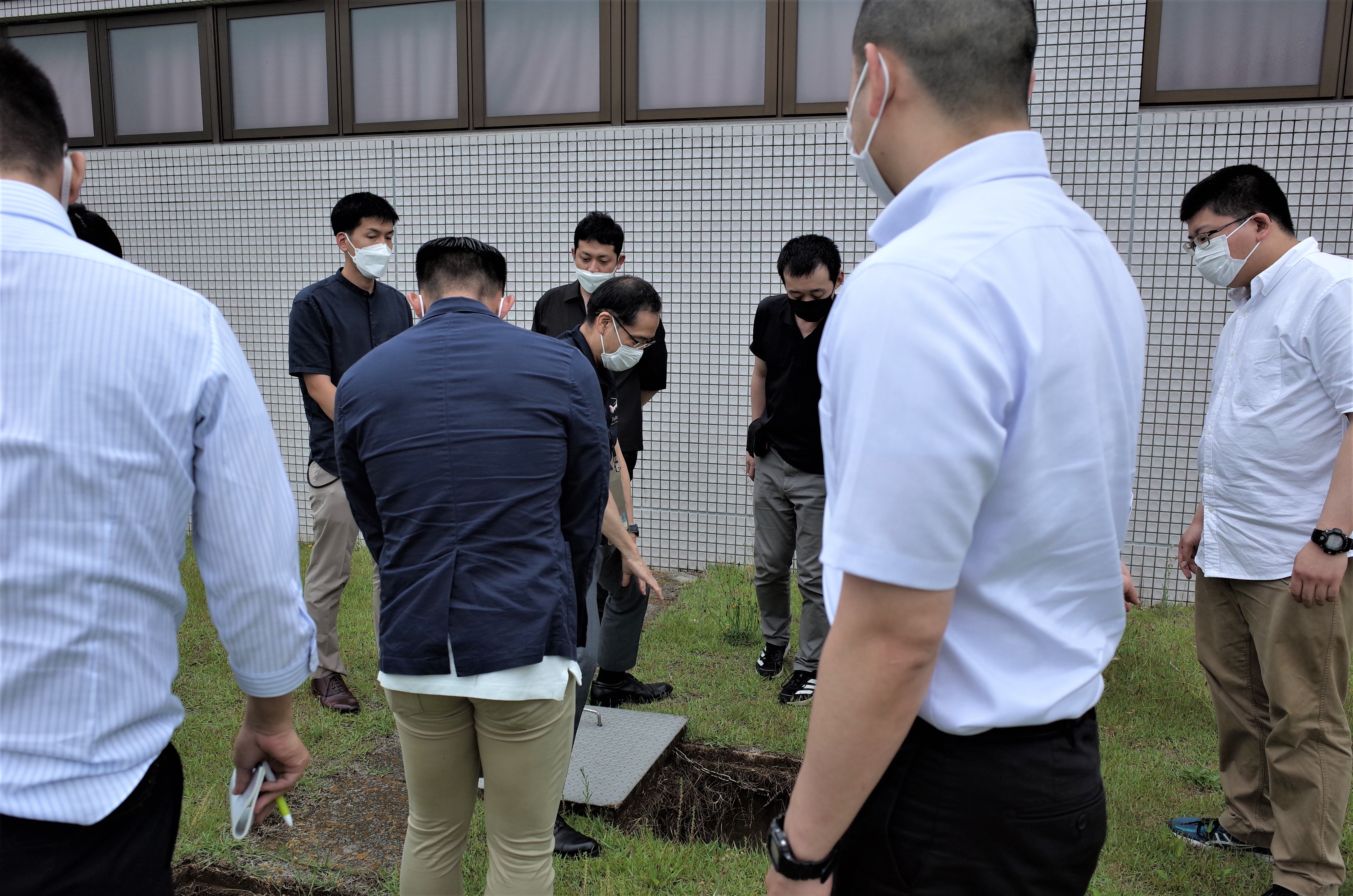 陸上自衛隊化学学校の学生たちが福島県立医科大学附属病院の放射線災害医療センターを訪問し、地面に設置された装置を見学している様子。