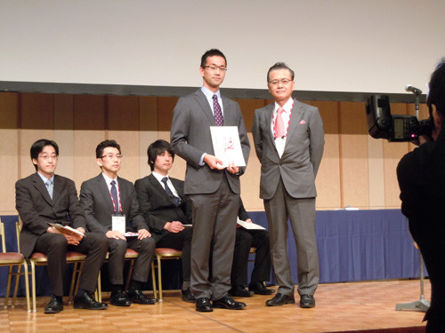 鈴木玲先生が日本消化器内視鏡学会平成27年度学会賞を受賞し、表彰式で賞状を持っている様子。