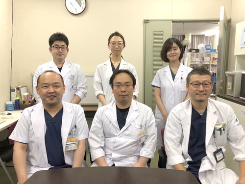 福島県立医科大学の医療チームが診療室でポーズをとっている写真。