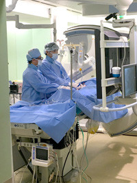 医療現場で肝臓の治療を行う医師たちが、手術用機器の前で準備をしている様子。