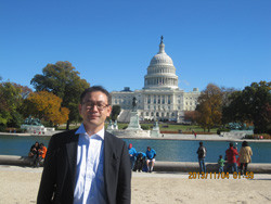 ワシントンDCの国会議事堂を背景に立つ男性の写真。秋の晴れた日で、周囲には観光客が見える。