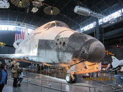 スペースシャトルが展示されている博物館の内部で、訪問者が見学している様子。