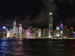 ビクトリアハーバーを背景にした香港の夜景、色とりどりのビルがライトアップされている。