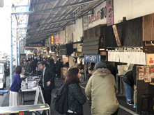 賑わいを見せる飲食店街の風景。多くの人々が行き交い、屋台や店舗が並ぶ様子。