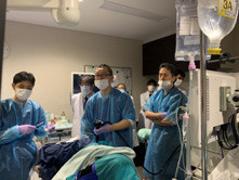 医療現場で手術を行う医師たちが集まり、患者の状態を確認している様子。