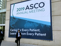 2019年のASCO年次総会の看板の前に立つ人物。医療に関する国際会議の様子を示す。