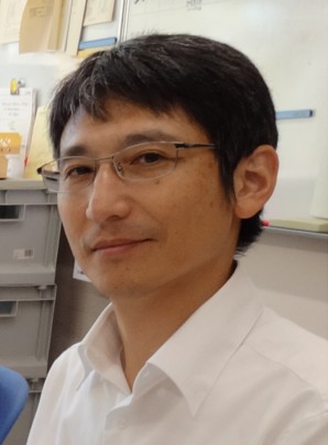 教授の立石善隆氏がスーツを着て正面を向いているポートレート。背景は無地でシンプル。