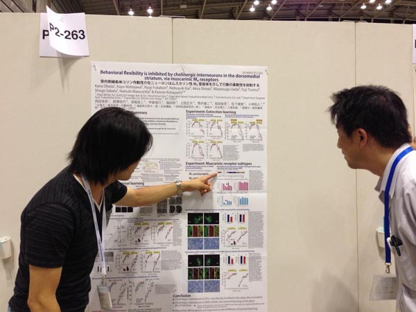 ポスターに掲載されたグラフを指さしながら説明している様子。