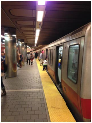 駅ホームで列車が停車しており、乗降する人々の様子。