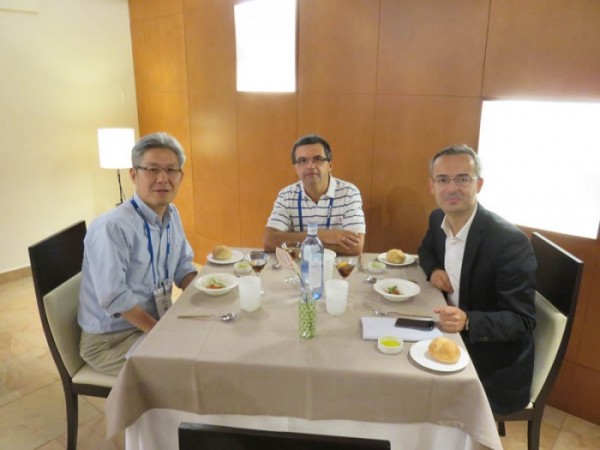 小林先生がJose Lanciego博士、Vania Broccoli博士とレストランで丸テーブルを囲んで座り、食事を楽しんでいる。