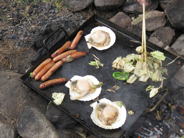 鉄板の上にホタテ、ソーセージ、キャベツなどが焼かれている。