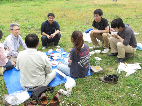 青いシートに座り食事を楽しんでいる様子。