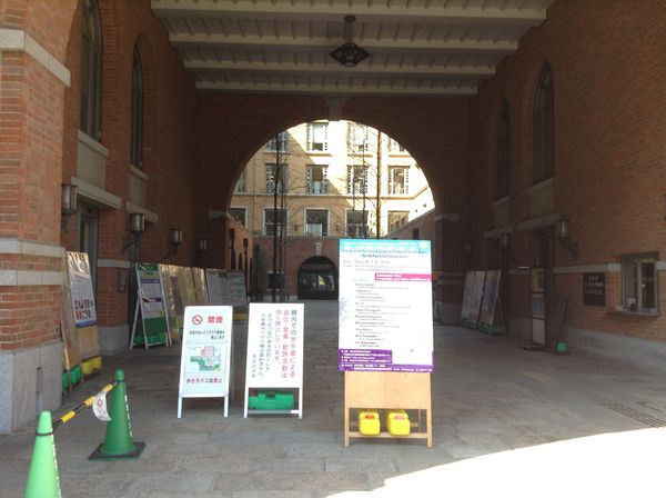 レンガ造りのアーチの下に掲示板や案内板が配置されている大学の通路。