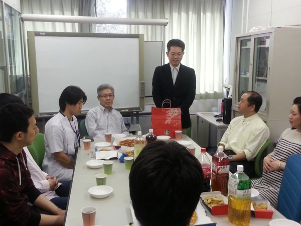 テーブルを囲み飲み物や食べ物が置かれた中、吉岡さんが挨拶をしている様子。