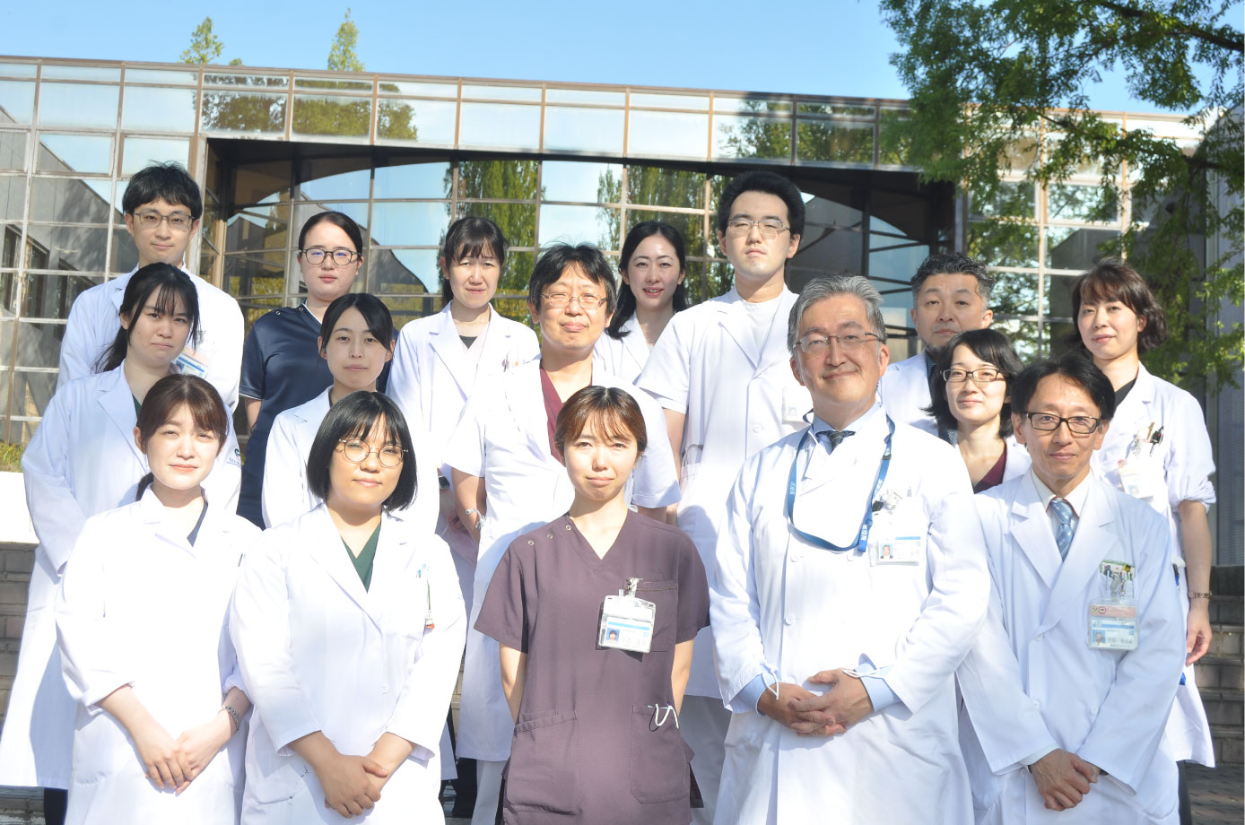 福島県立医科大学の医師たちが白衣を着て集合している写真。背景には大学の建物が見える。