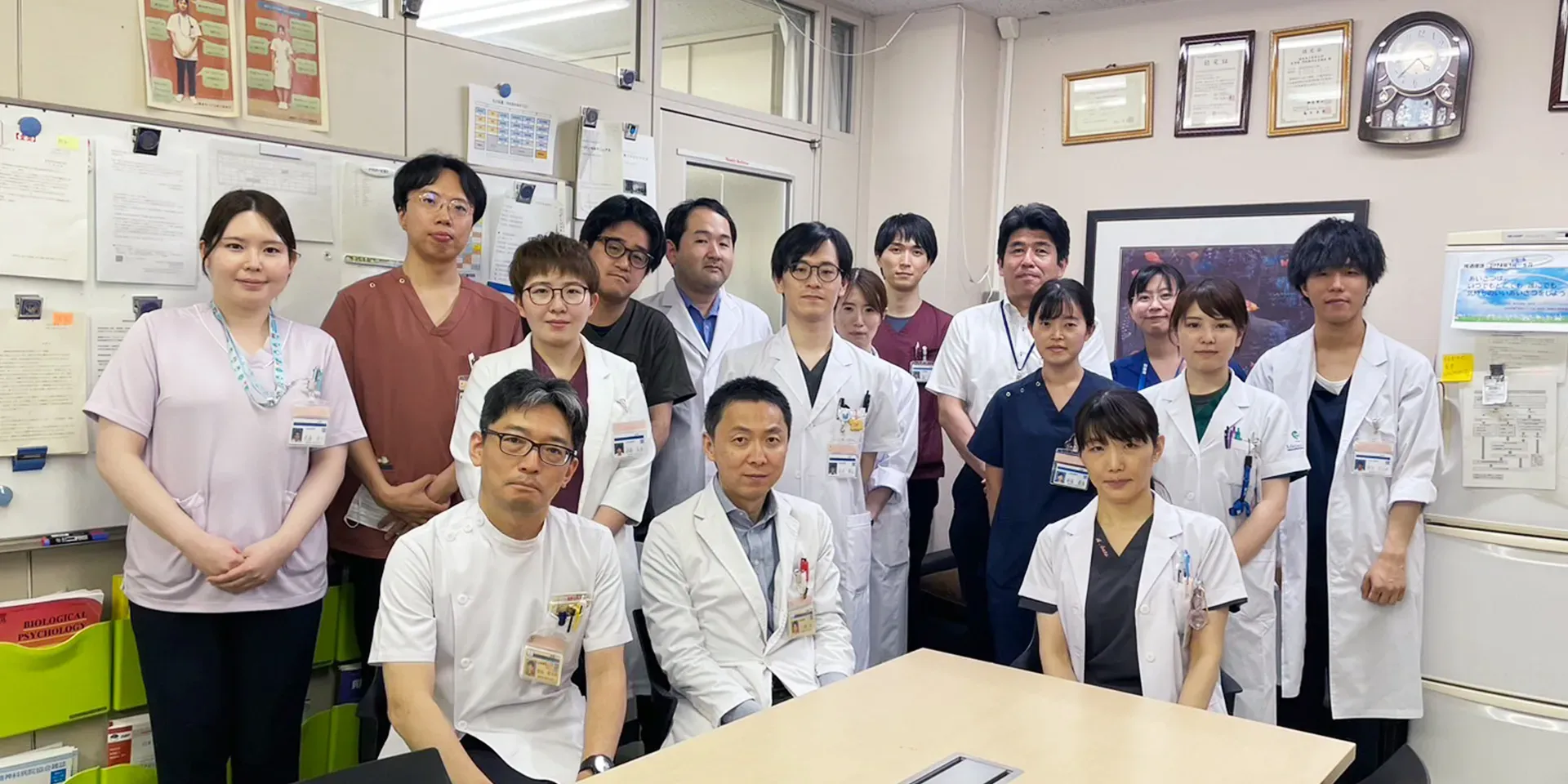 医療に関する会議が行われている室内の様子。参加者がテーブルに座り、プレゼンテーションを聴いている。